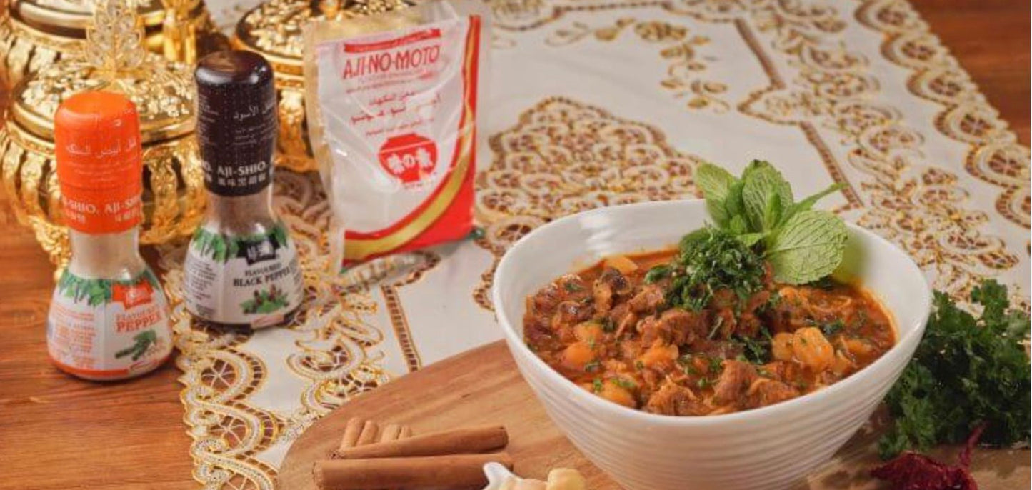 Aji-No-Moto seasoning displayed alongside a flavorful dish on an ornate table setting.