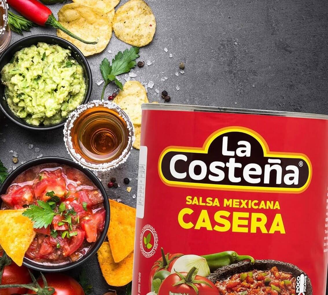 La Costeña Salsa Casera Roja can with dishes, tomatoes, and snacks, adding Mexican flavor to meals.
