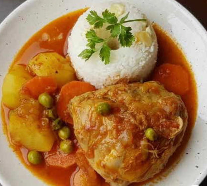 Delicious chicken stew with vegetables and rice, garnished with cilantro on a white plate.