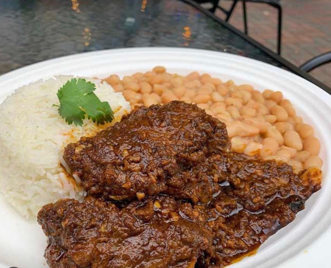 Plated dish of rice, beans, and tender meat in rich sauce, garnished with fresh cilantro.